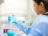 A scientist carefully holds a 50 mL conical tube containing a vivid blue liquid, poised for precise experimentation and analysis in the laboratory